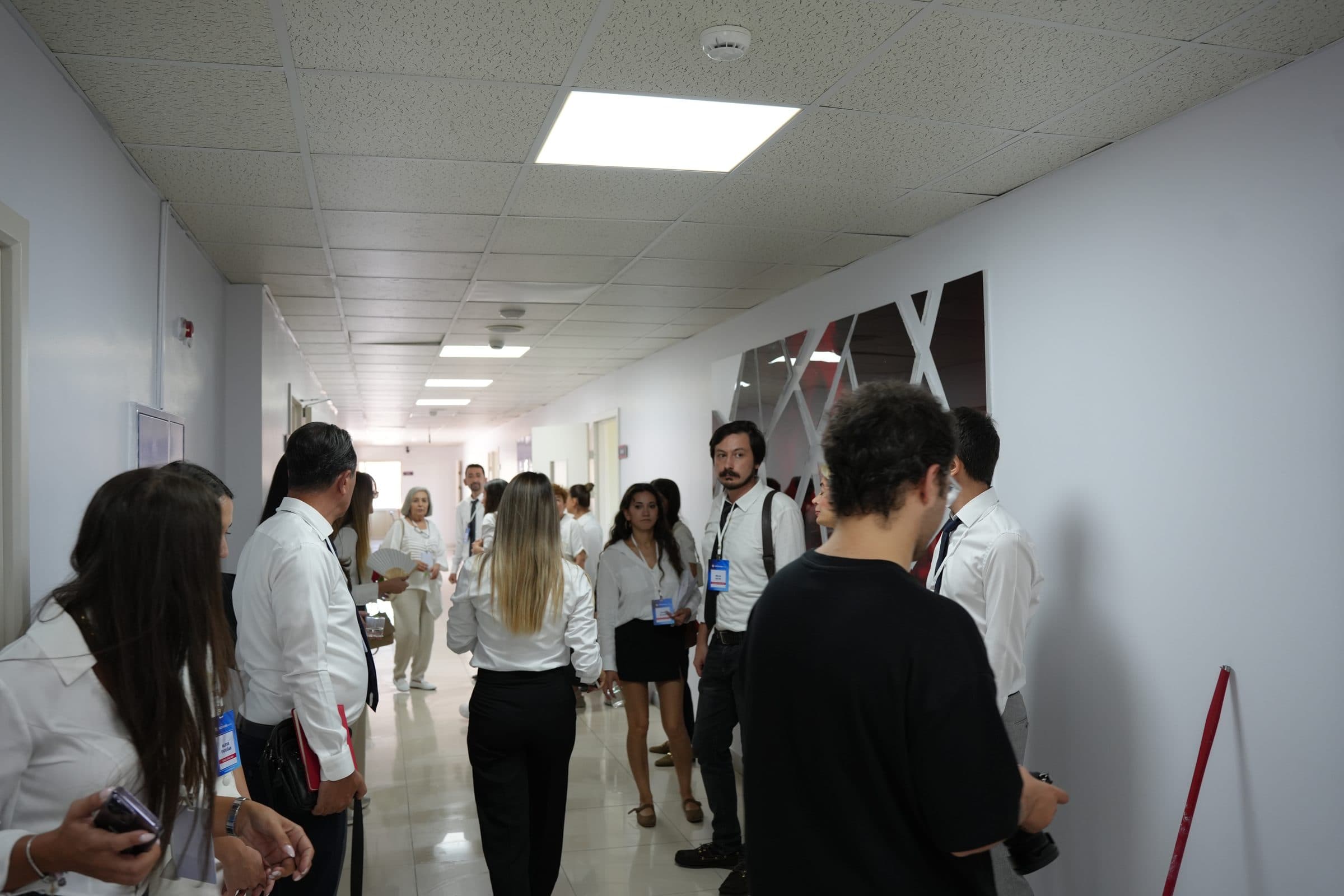Beyaz duvarlı, aydınlık okul koridorunda binayı gezen öğretmenler.